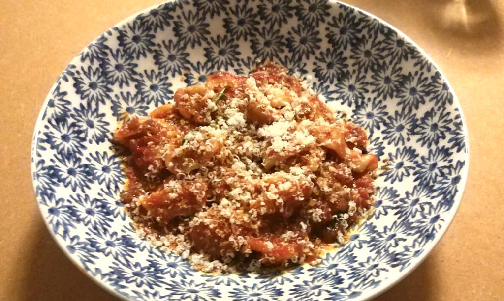 A bowl of home made orecchiette pasta and tomato and red onion sauce, topped with parmesan.