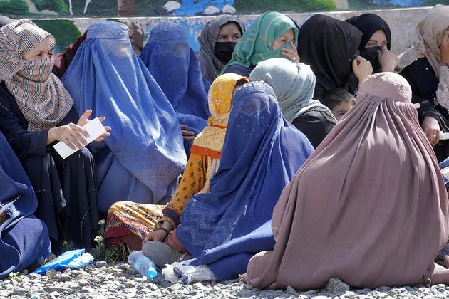 Afghan women wait to receive food rations.