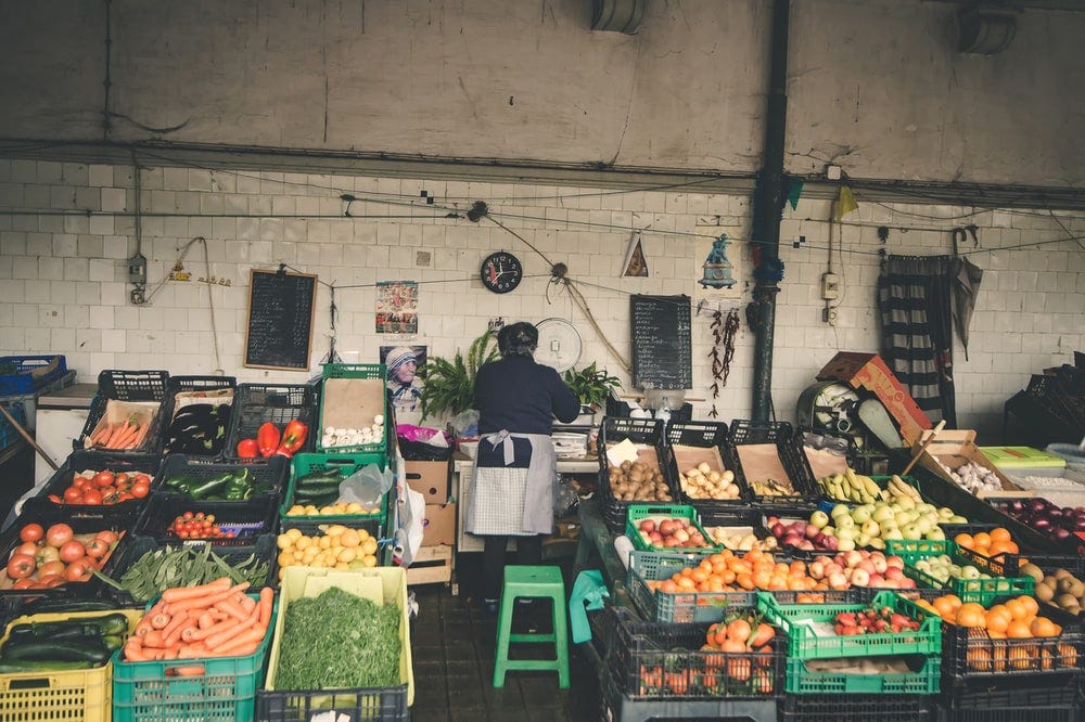 person standing at vegetable and fruitstand