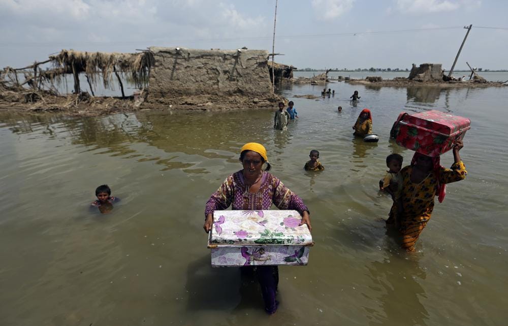 FILE - Women carry belongings salvaged from their flooded home after monsoon rains, in the Qambar Shahdadkot district of Sindh Province, of Pakistan, Sept. 6, 2022. Earth’s warming weather and rising seas are getting worse and doing so faster than before, the World Meteorological Organization warned Sunday, Nov. 6, 2022, in a somber note as world leaders started gathering for international climate negotiations in the Egyptian resort of Sharm el-Sheikh. (AP Photo/Fareed Khan, File)