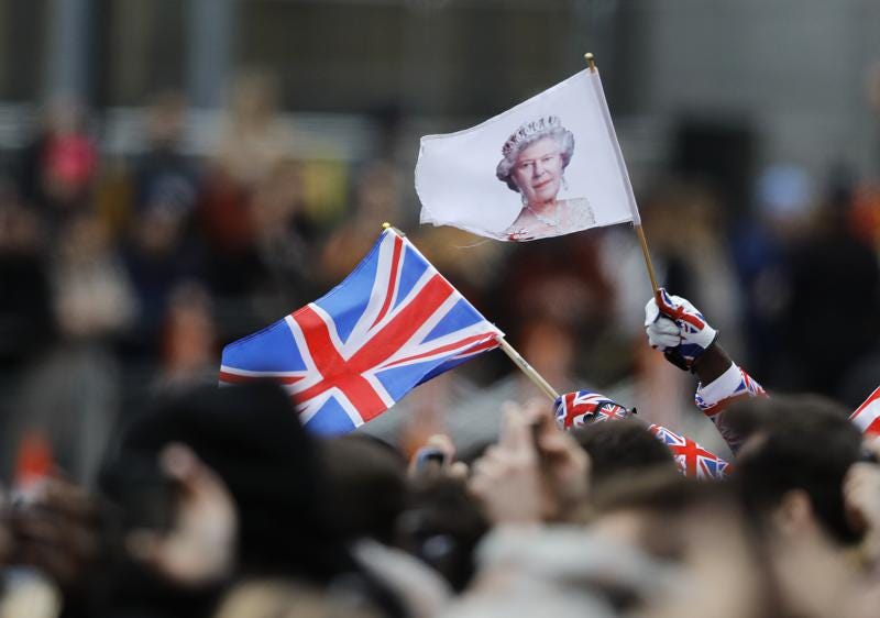 FILE - A man waves a British union flag and a flag bearing the image of Britain's Queen Elizabeth II ahead of the annual Commonwealth Day service at Westminster Abbey in London, Monday, March 9, 2020. After seven decades on the throne, Queen Elizabeth II is widely viewed in the U.K. as a rock in turbulent times. But in Britain’s former colonies, many see her as an anchor to an imperial past whose damage still lingers. (AP Photo/Frank Augstein, File)