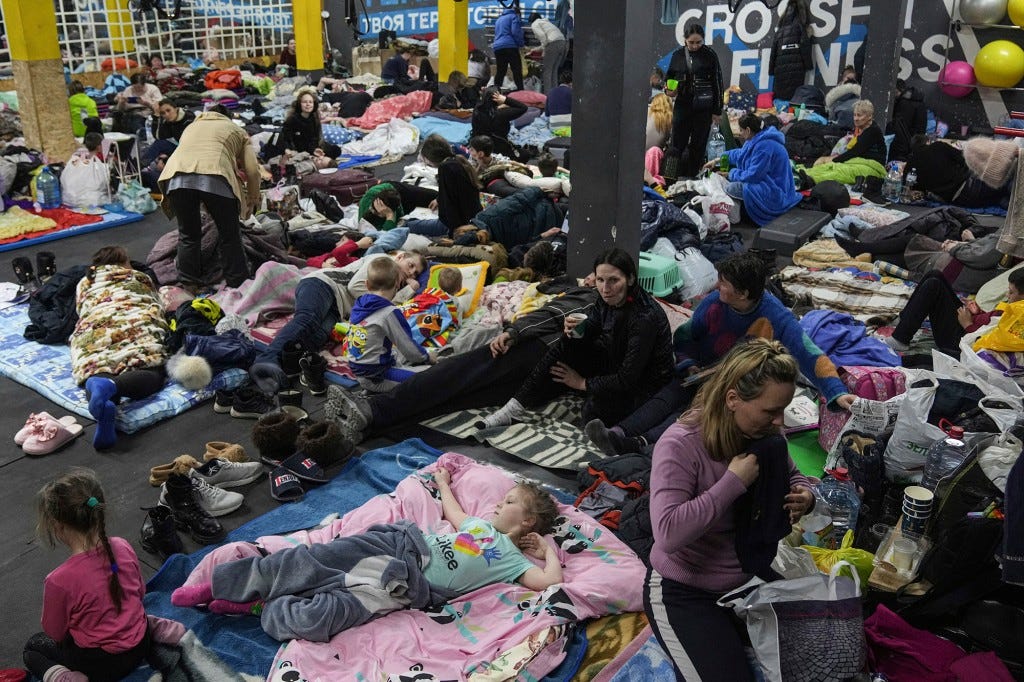 People sit and lie on the floor in the improvised bomb shelter in a sports center