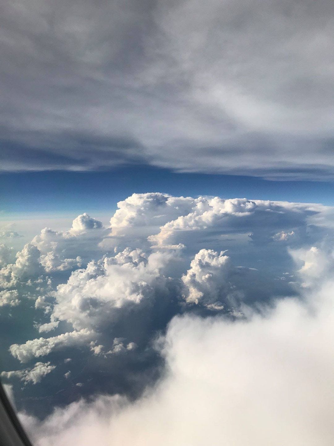 billowing white clouds and blue sky, from the window of an airplane