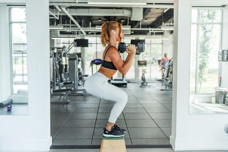 A woman does a squat while holding weights.