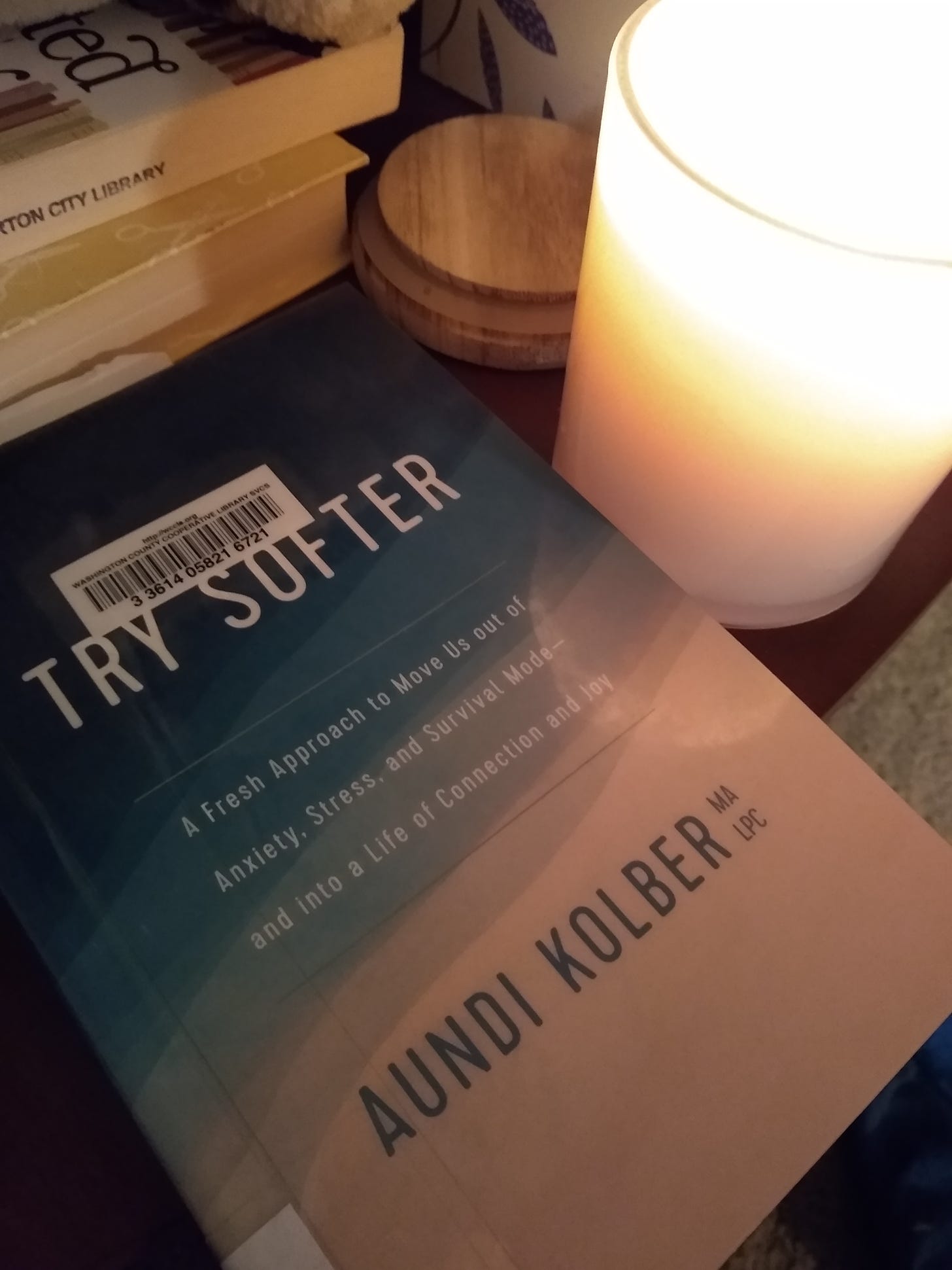 The book Try Softer by Aundi Kolber and a lit candle