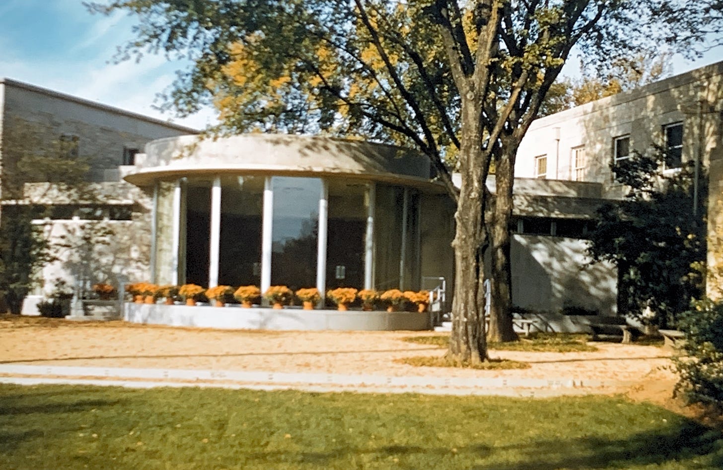Photo showing a circular room with glass windows along the outside, with planters of mums on the ledge outside surrounding it.