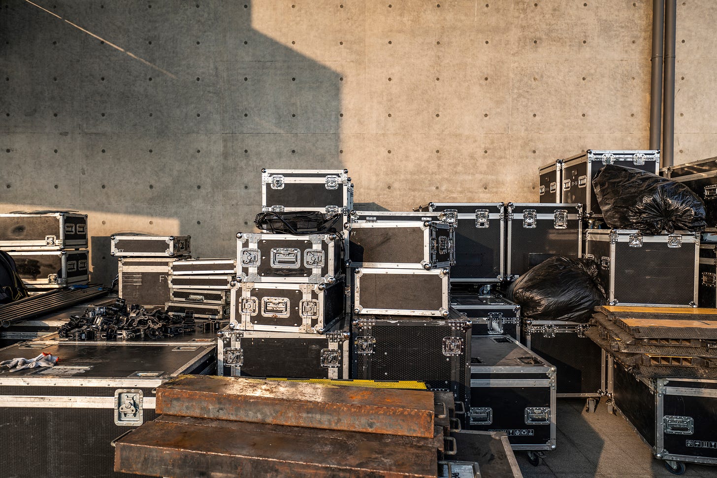 A stack of concert road cases, traditional black with silver reinforcement , a few rusty ramps and cable protectors. Very typical backstage scene (I worked in the industry for a long time)