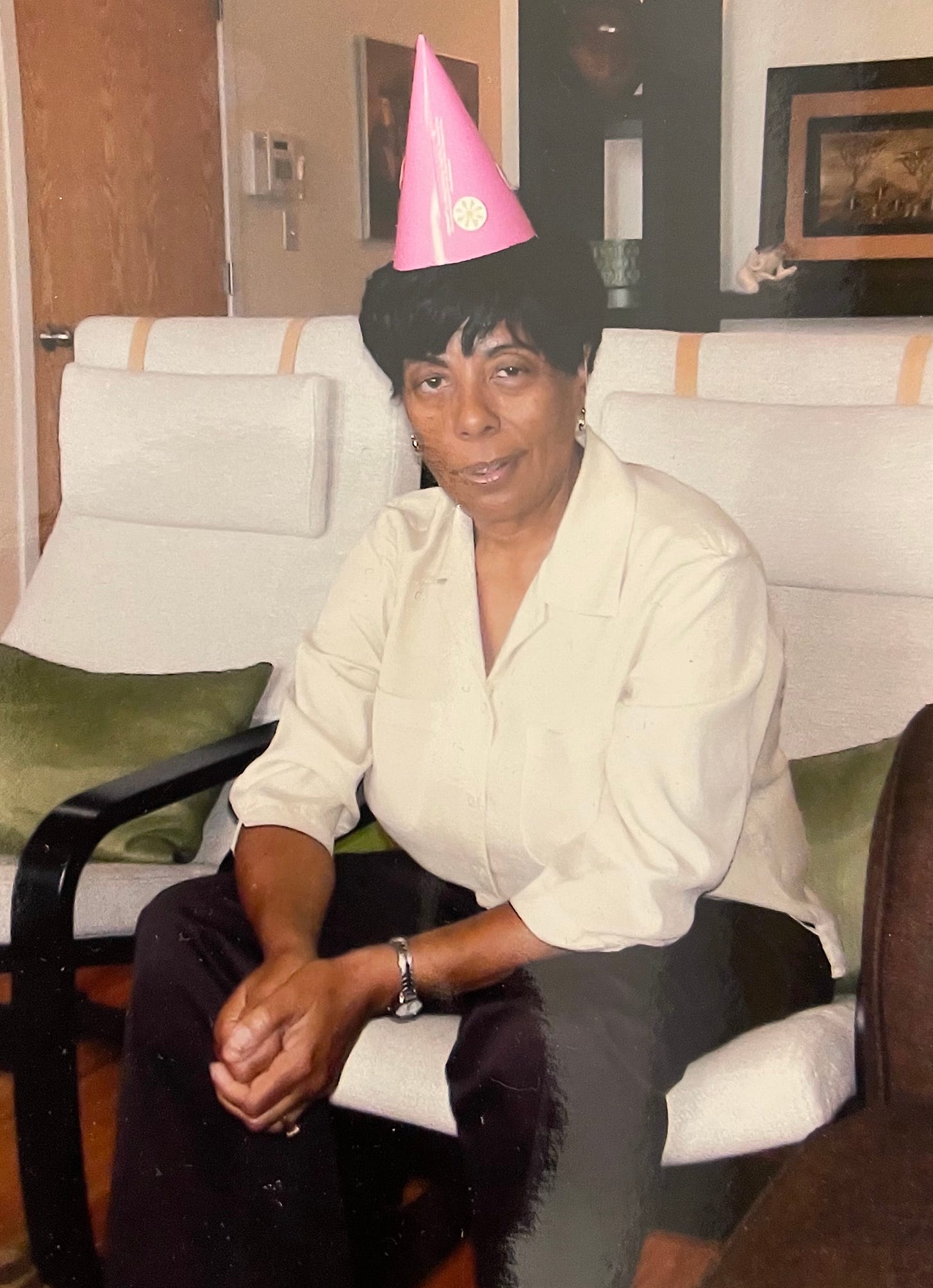 Jemar's mom sitting down with a pink party hat on her head