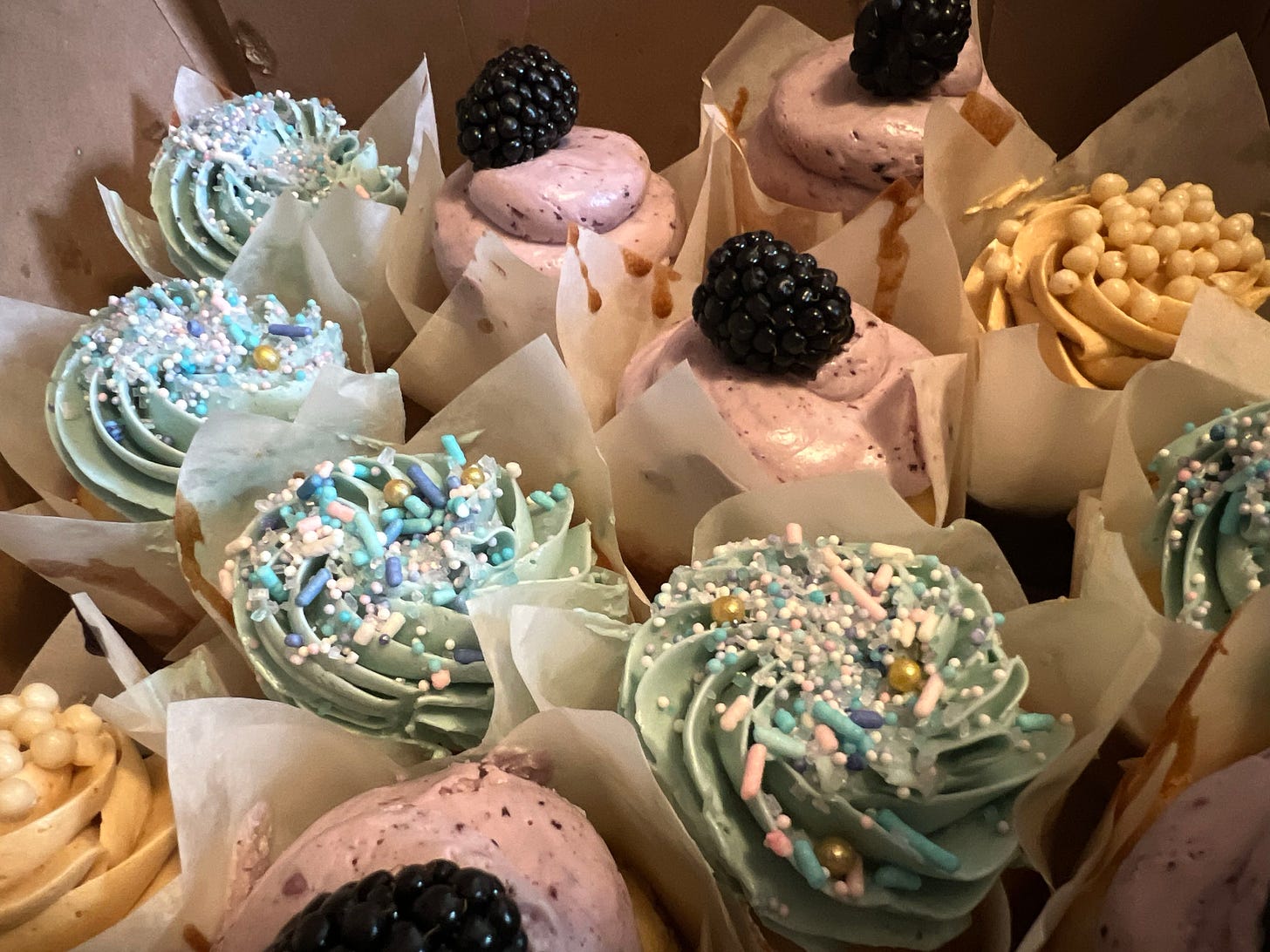 a close up of a box full of fancy decorated cupcakes