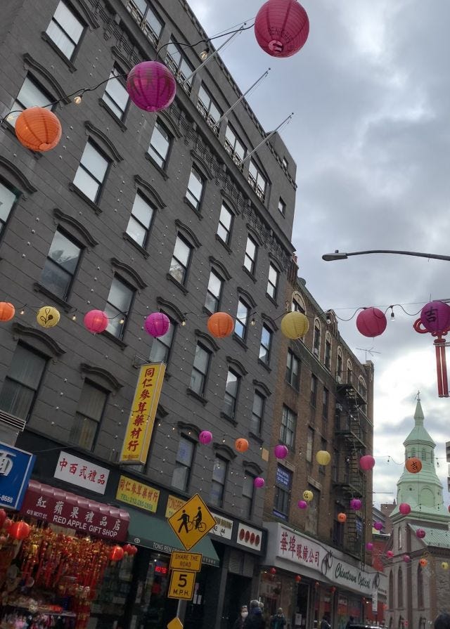 image description: chinatown streets with lanterns strung across the roofs.