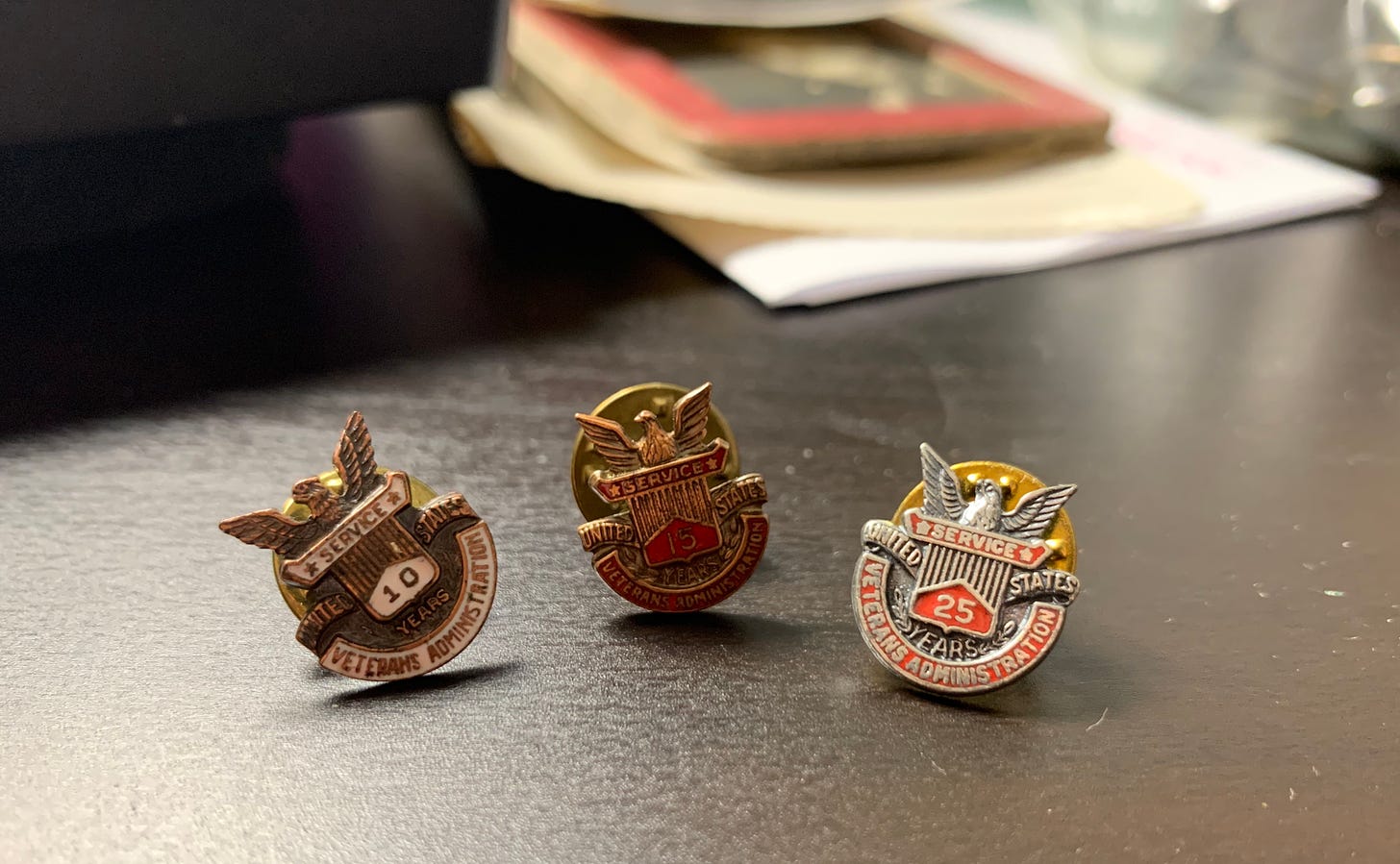 Three pins featuring eagles and the words Veterans Administration and Service with a 10, 15, and 25 respectively.