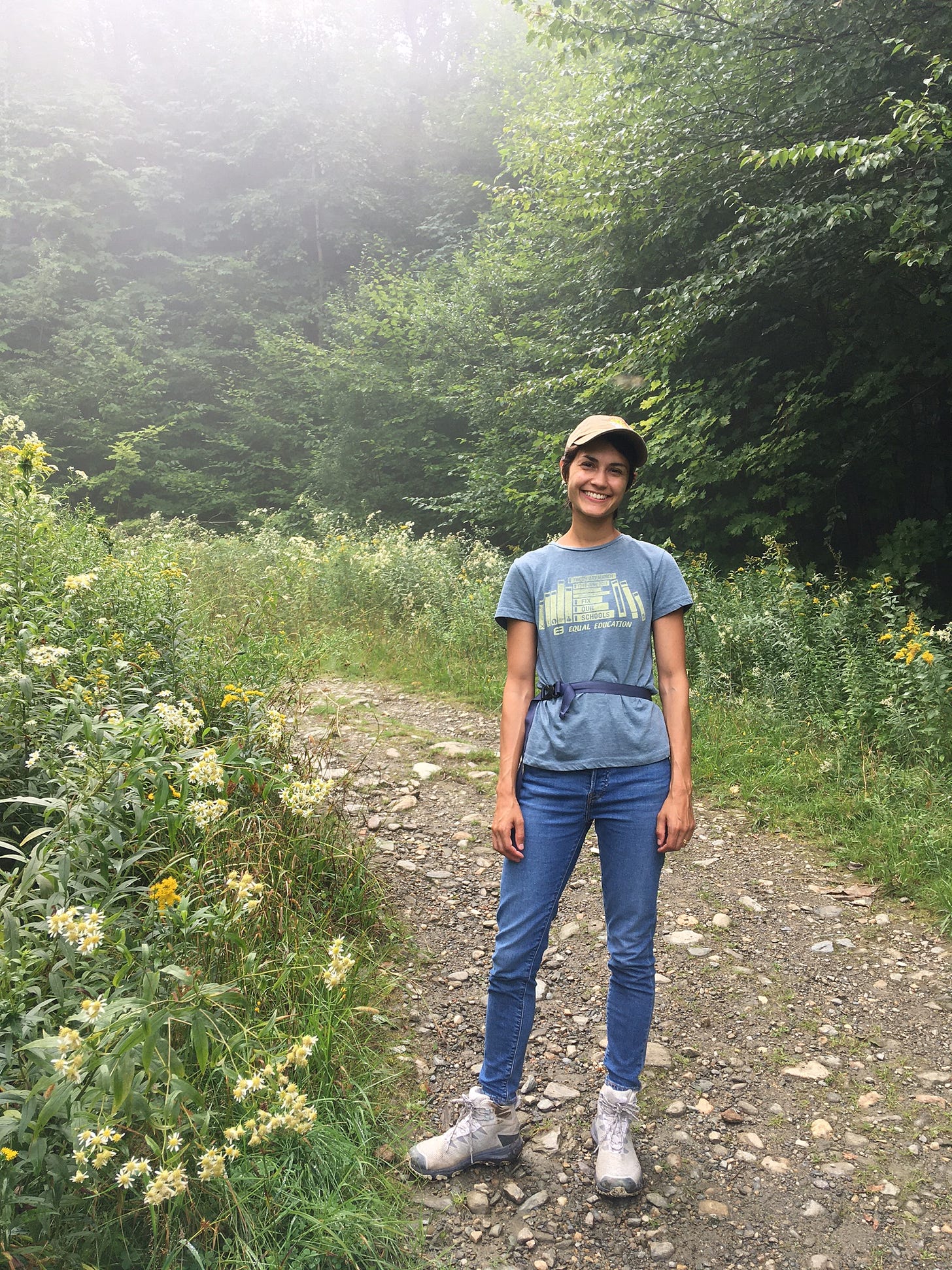 Priya stands smiling on the trail up the mountain