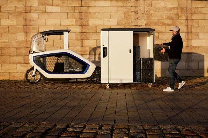 Onomotion e cargo bike and container viewed from the side as a man loads a parcel