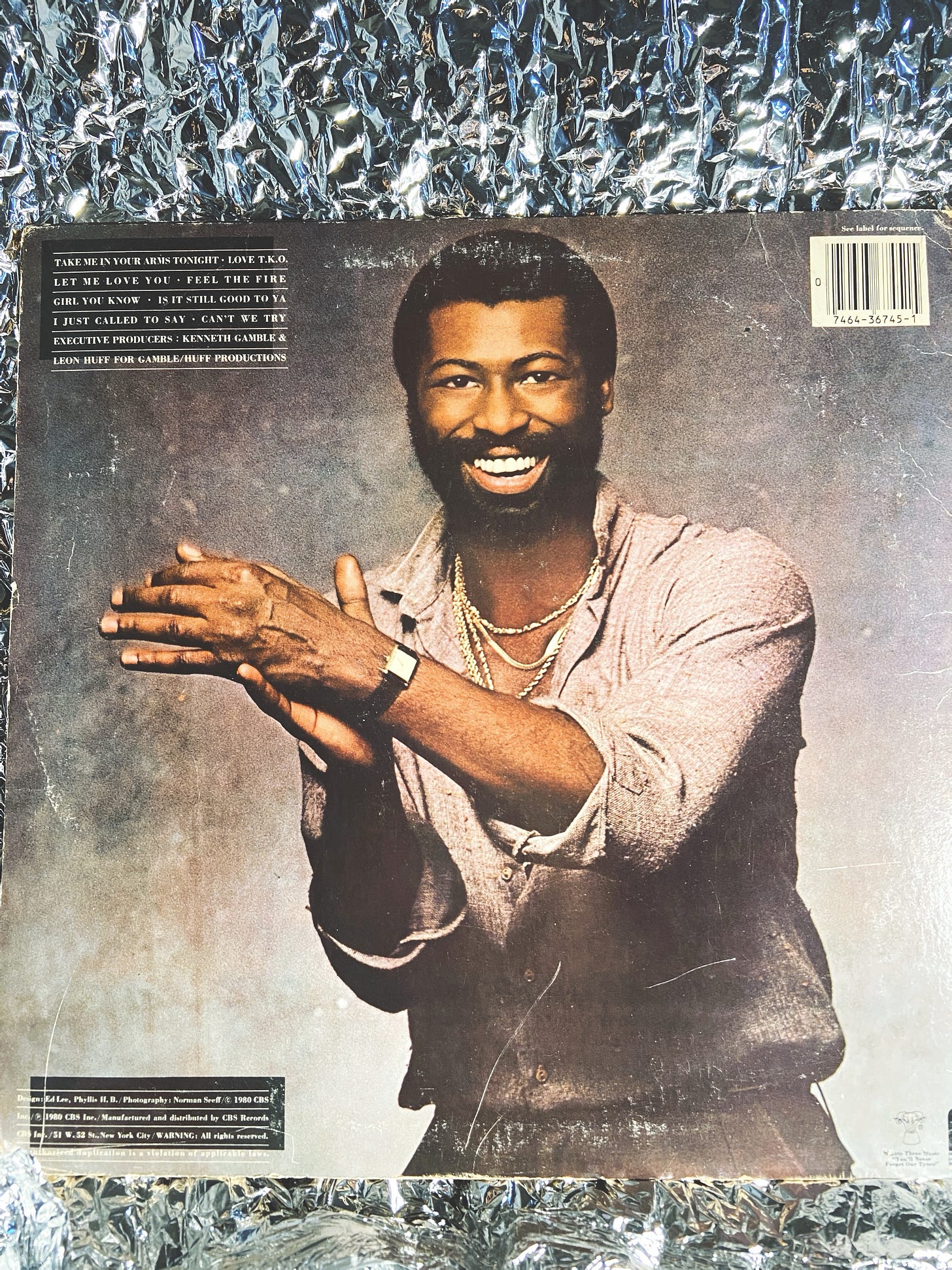 image of the back cover of TP by Teddy Pendergrass, placed in front of a wrinkled foil material