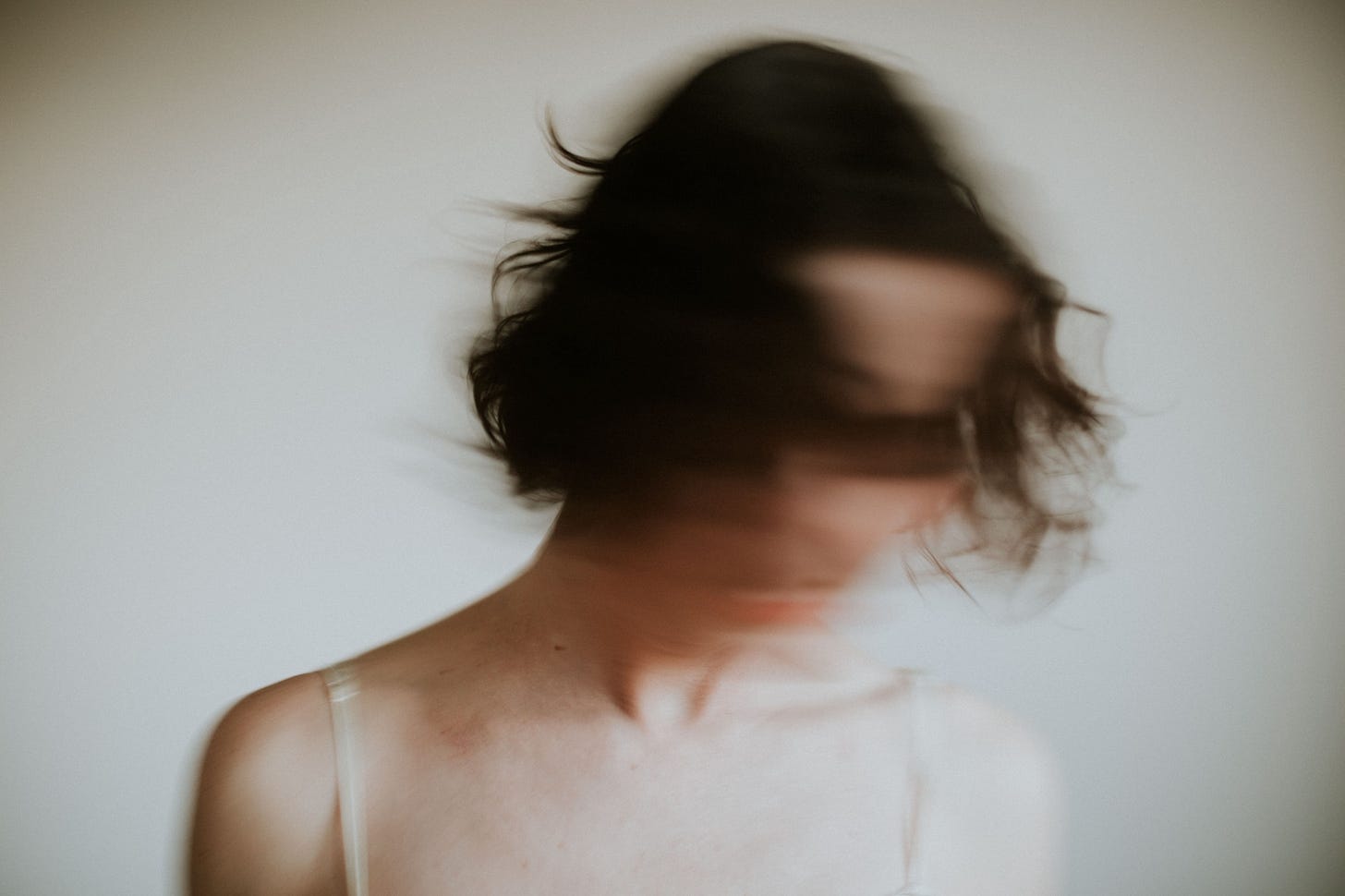 Blurred woman with dark hair shakes her head from side to side.