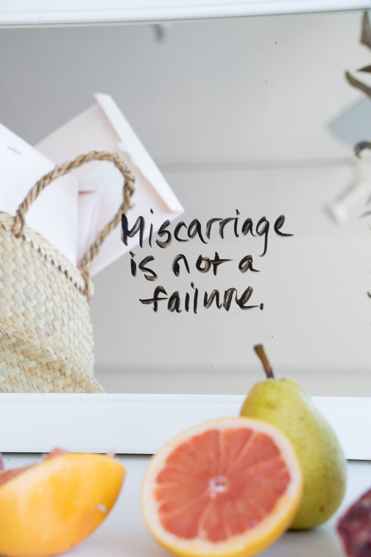 half grapefruit and a pear on a counter top with the words "Miscarriage is not a failure" written over top