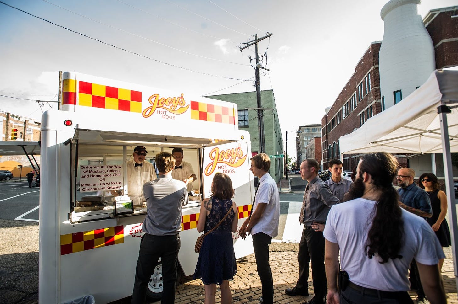 A picture of Joey's Hot Dog truck serving wedding guests on a city street. 