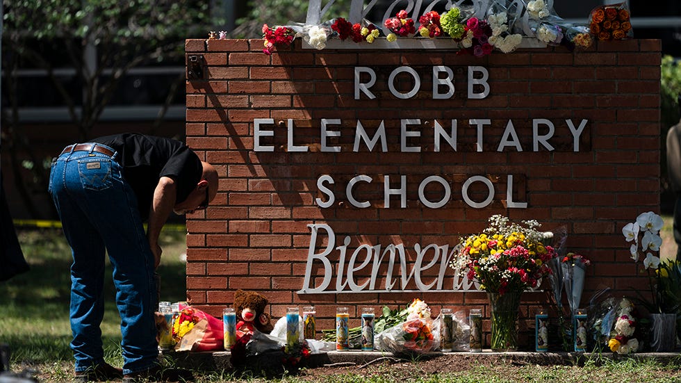 A person lights a candle outside Robb Elementary School in Uvalde, Texas