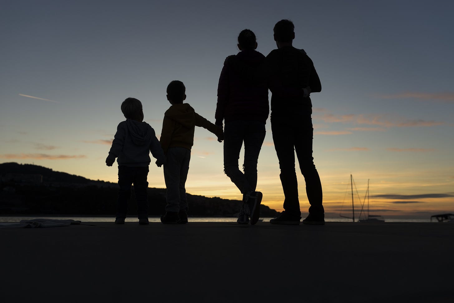 The silhoutte of a family holding hands at sunset.
