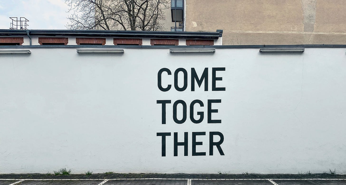 Photo of a white wall painted with the words "Come Together"