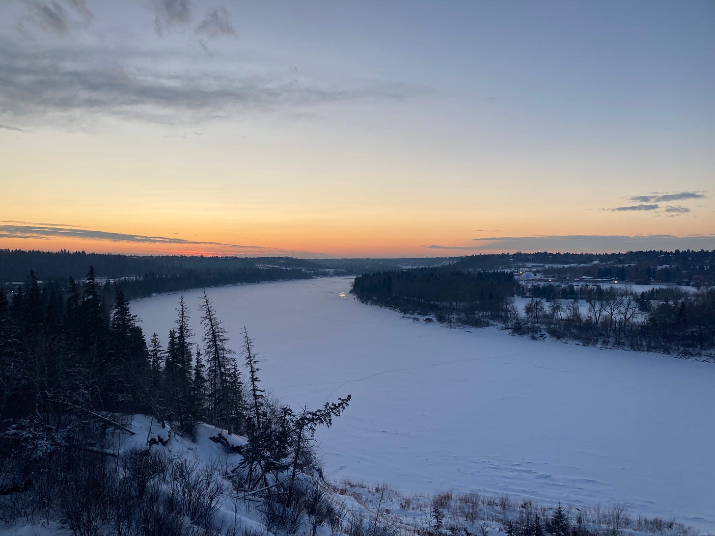 大きな河川が凍り、真っ白になっている。うっすらと夕焼雲が低い空に広がる。