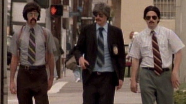 A still from the Beastie Boys "Sabotage" video. The Beasties are dressed like 70s TV detectives and walking toward the camera.