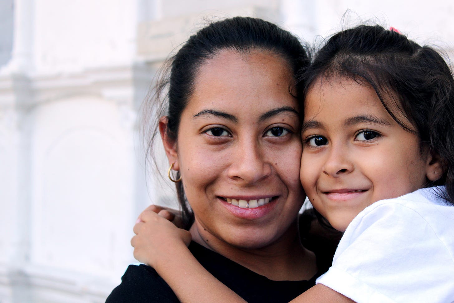 Young Hispanic mother holding her young daughter in her arms