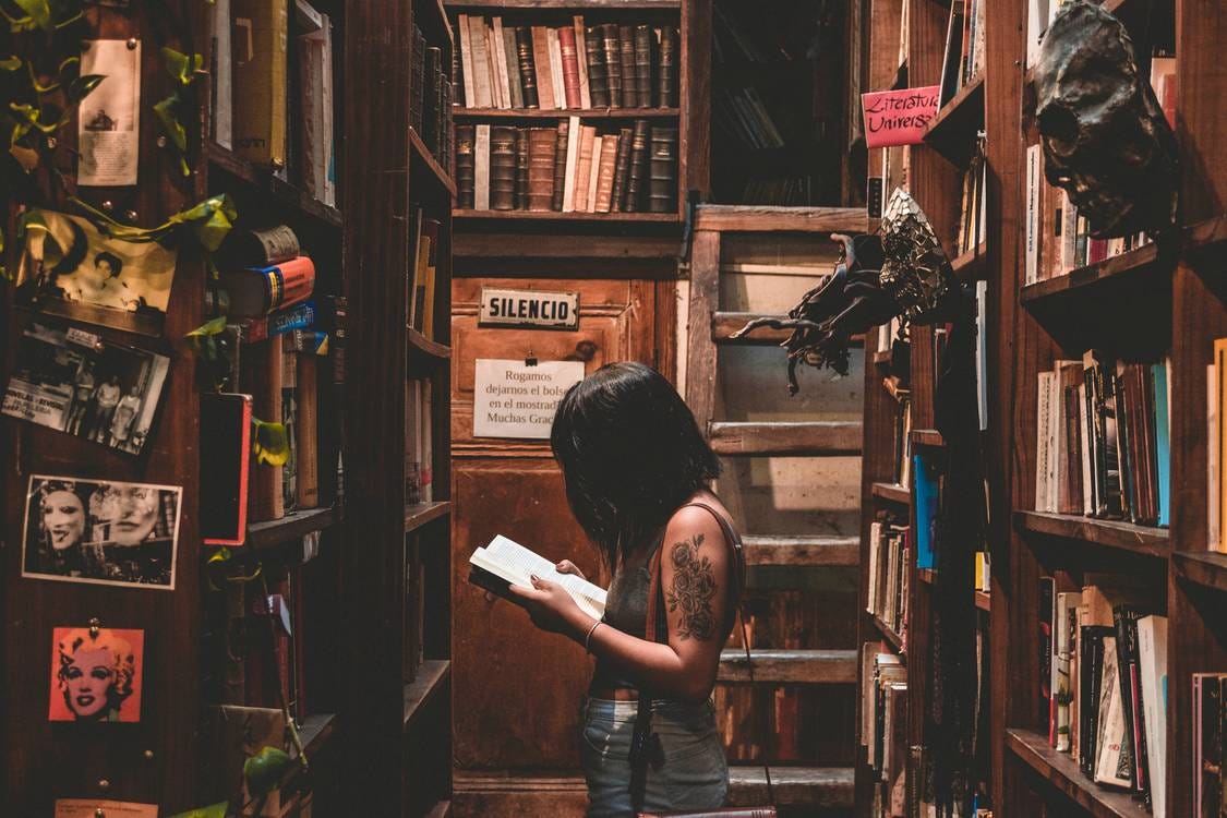 Woman Standing In Library Room While Reading Book