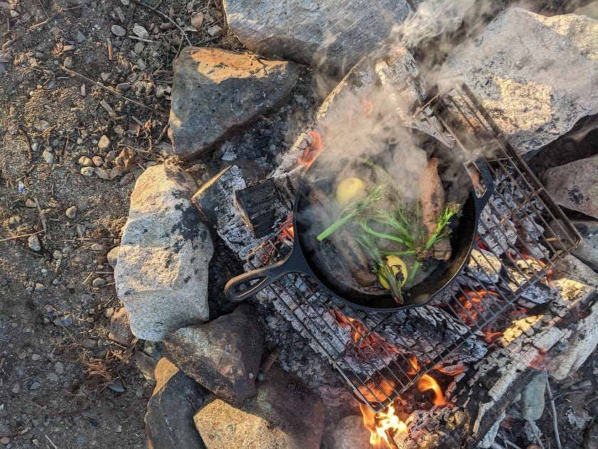 a cast iron cooks over a campfire