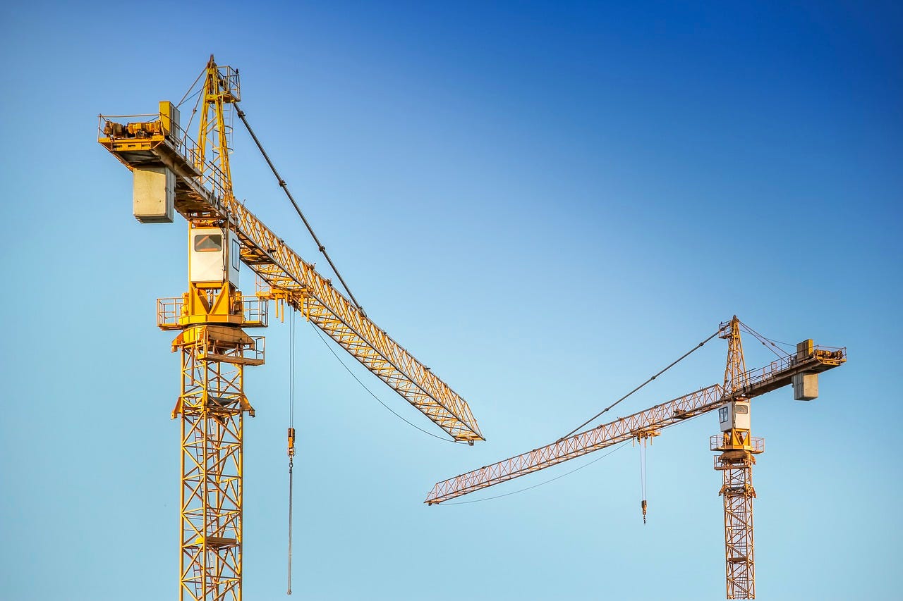 tops of two yellow cranes in front of blue sky