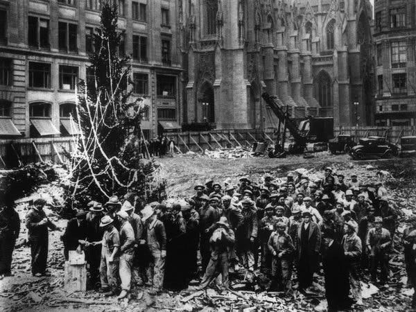 Workers excavating the site for Rockefeller Center in Midtown lined up by a Christmas tree, the first mounted there, on Dec. 24, 1931.