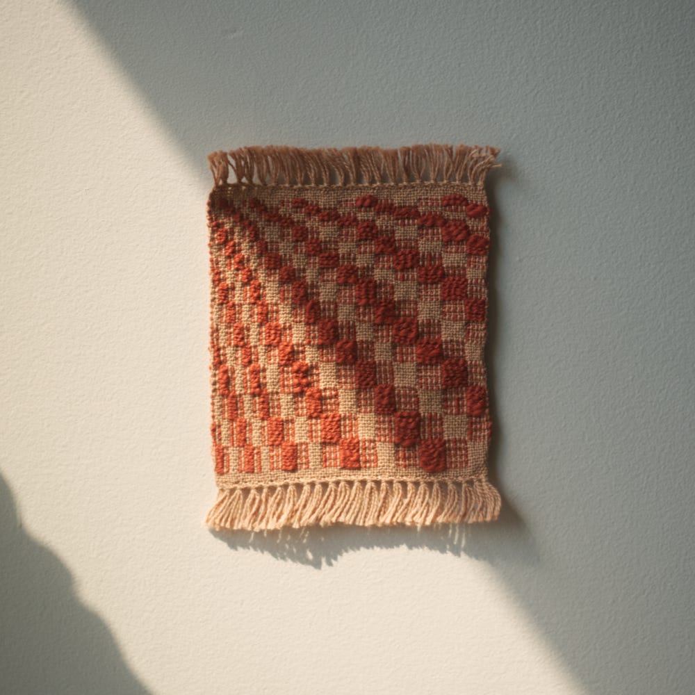 A small woven sample with diagonal lines going from top left to bottom right