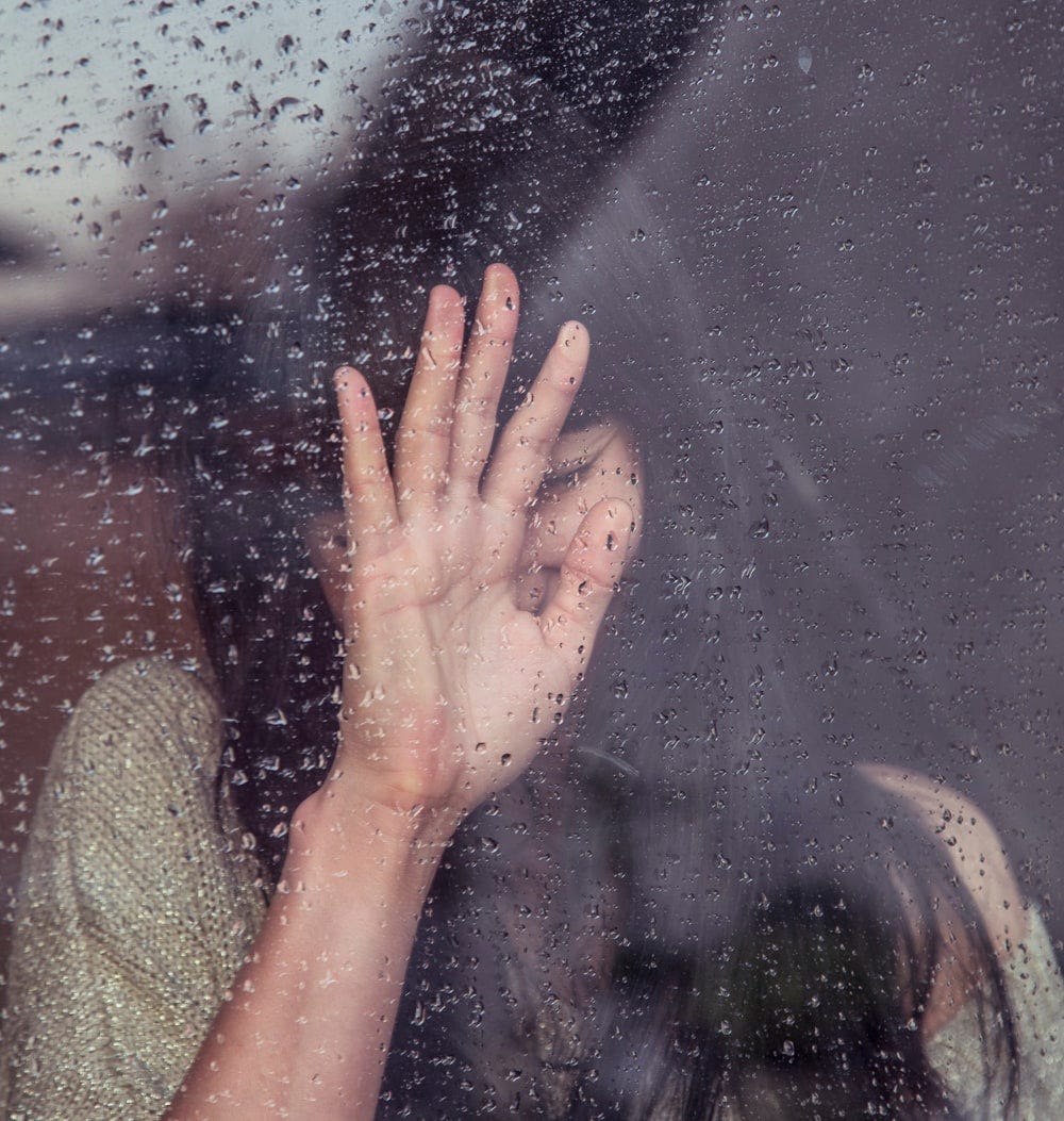 woman touch rainy glass