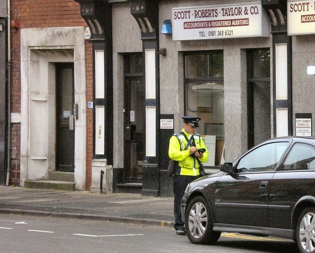 Traffic warden issuing a ticket to a black parked car