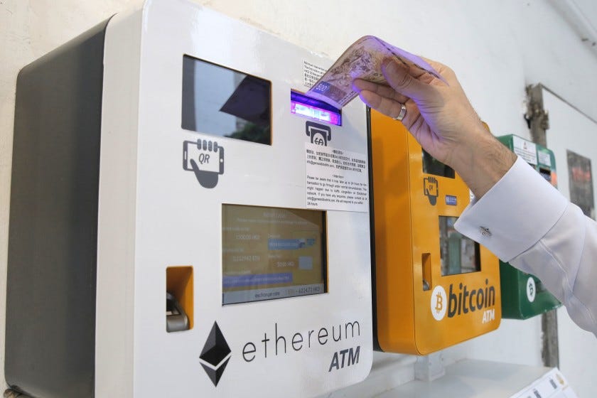 A man uses an Ethereum ATM next to a bitcoin ATM FILE 