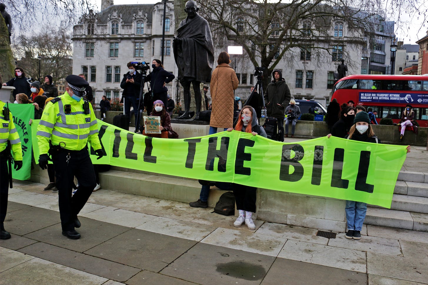 Protesters hold a banner saying "kill the bill" in front of a statue of Gandhi in London.