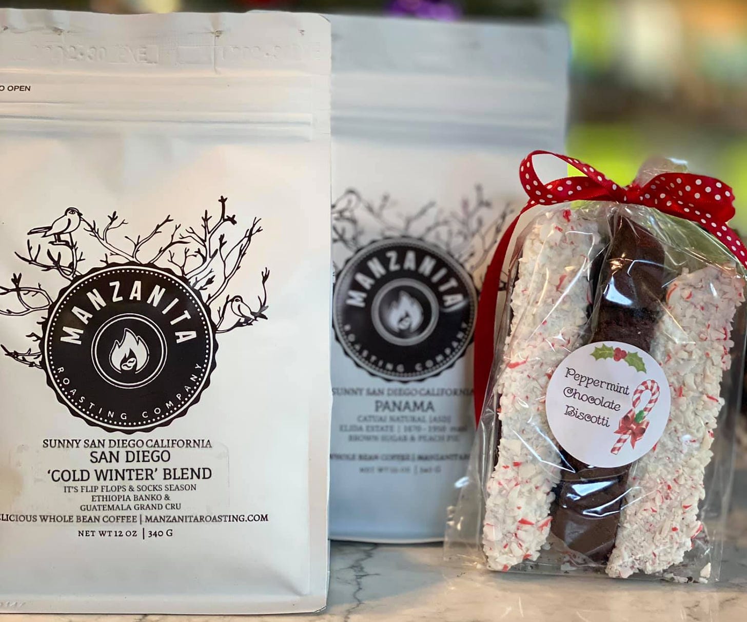 Two bags of Manzanita Roasting Coffee and a packaged Peppermint and Chocolate Biscotti holiday gift box offering.
