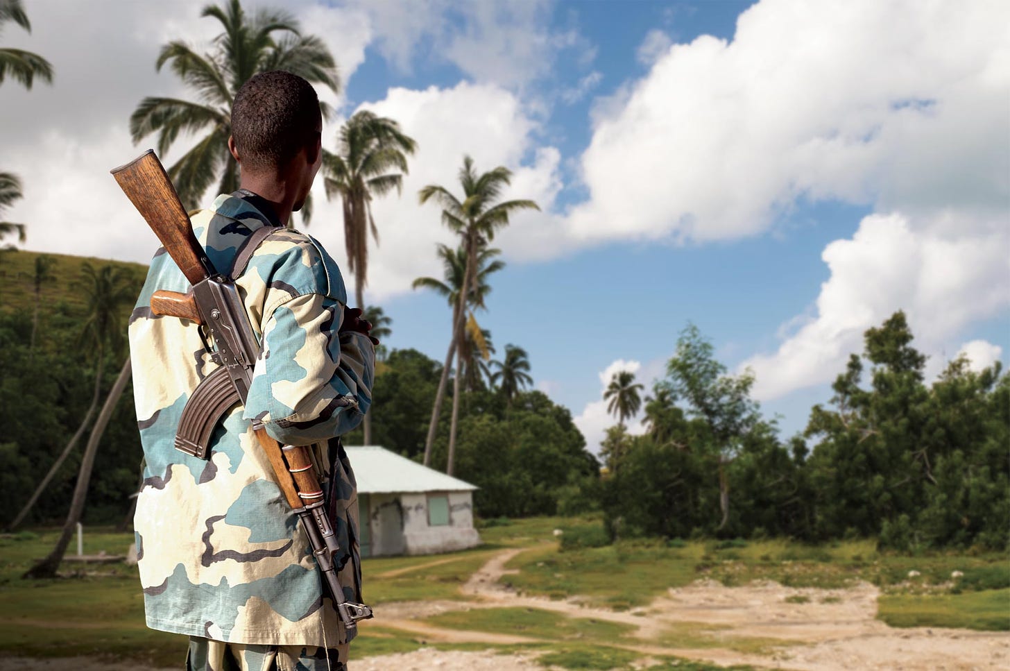 Colored man with an AK-47 rifle in a Haitian landscape