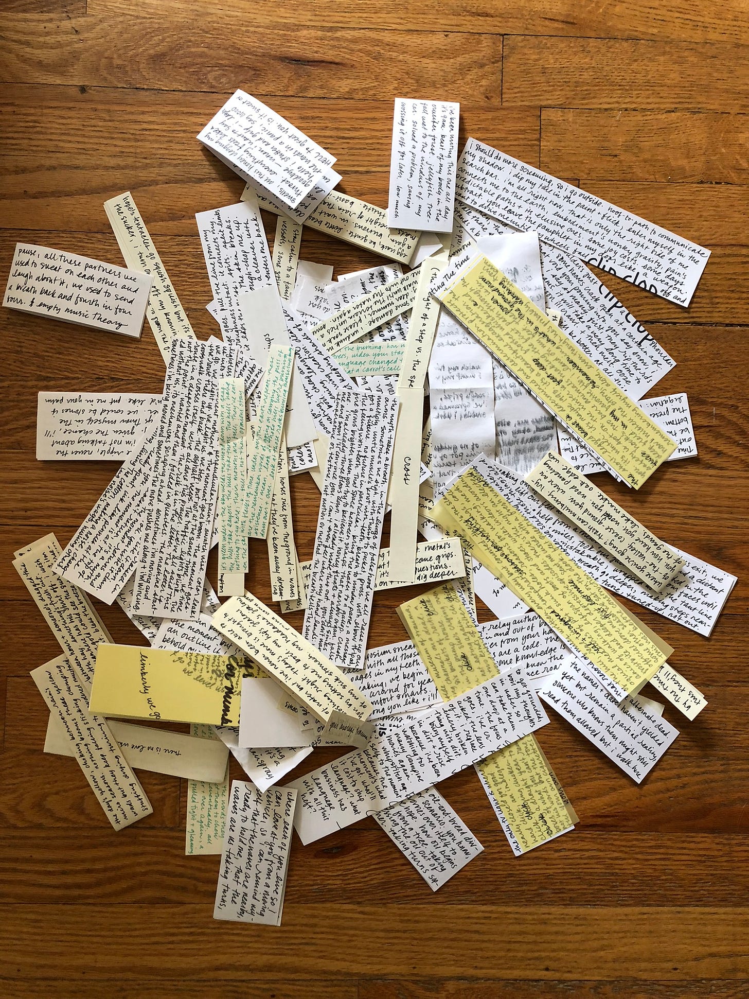 a pile of various sizes, shapes, and colors of handwritten ink on paper in a messy pile on a wood floor