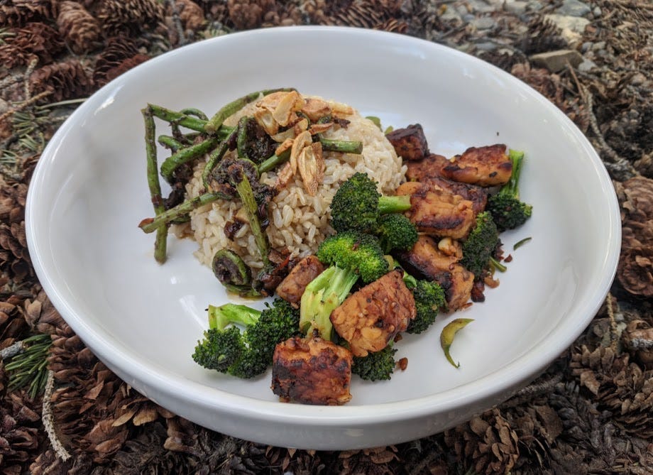 tempeh, broccoli, brown rice and fiddleheads in a bowl