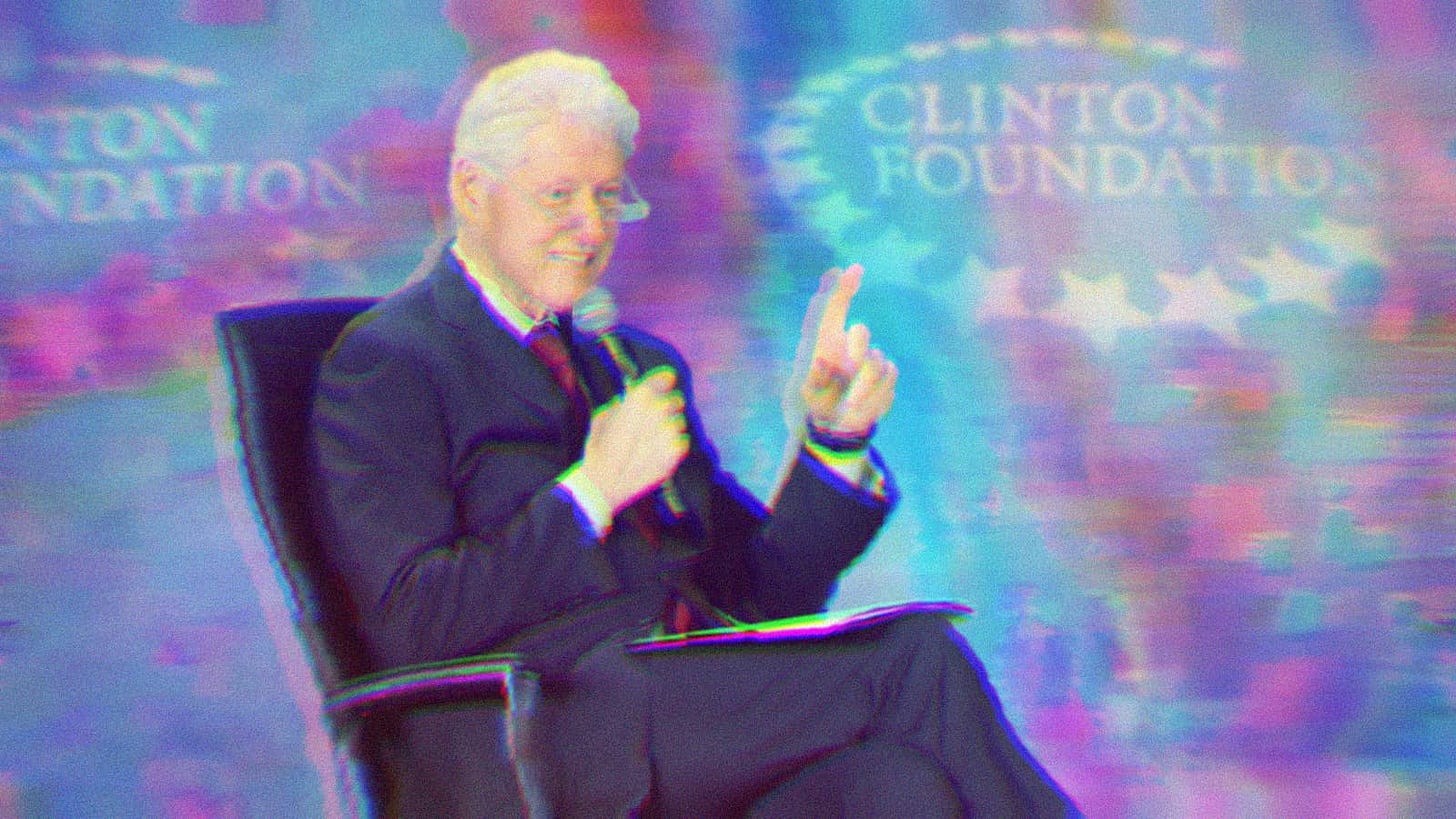 Bill Clinton sitting in a chair, pointing and holding a microphone. A Clinton Foundation banner sits in the background.