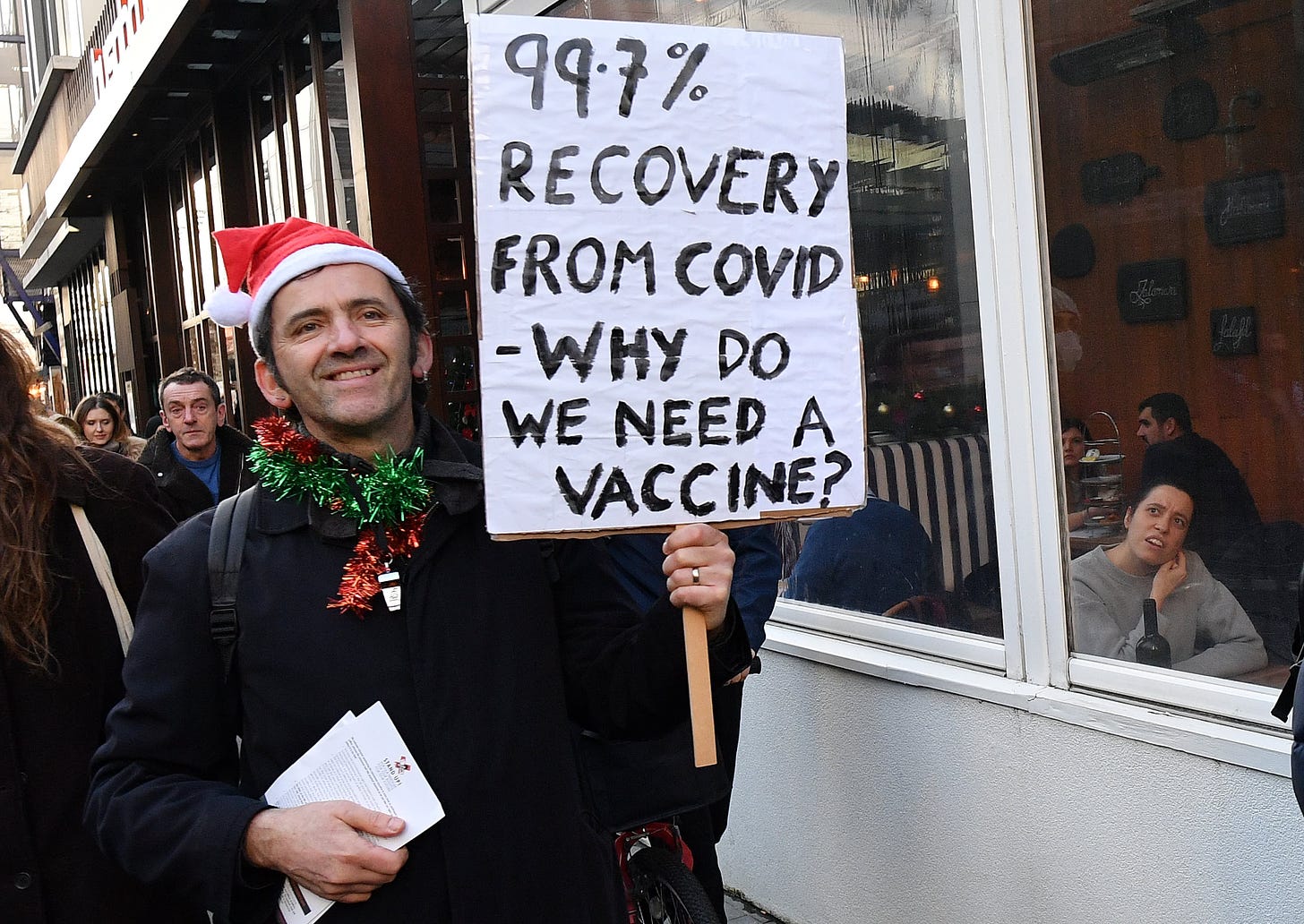 Covid protestor holding a sign saying 99.7% recover
