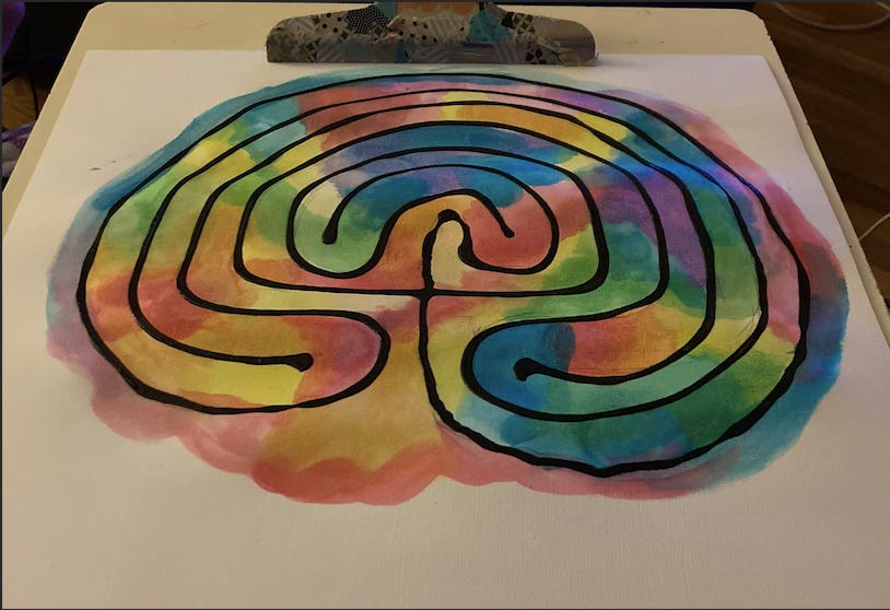 A watercolor labyrinth design with a raised black outline on a clipboard