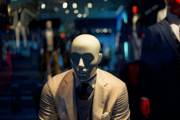 A sad mannequins sitting in a dark store.