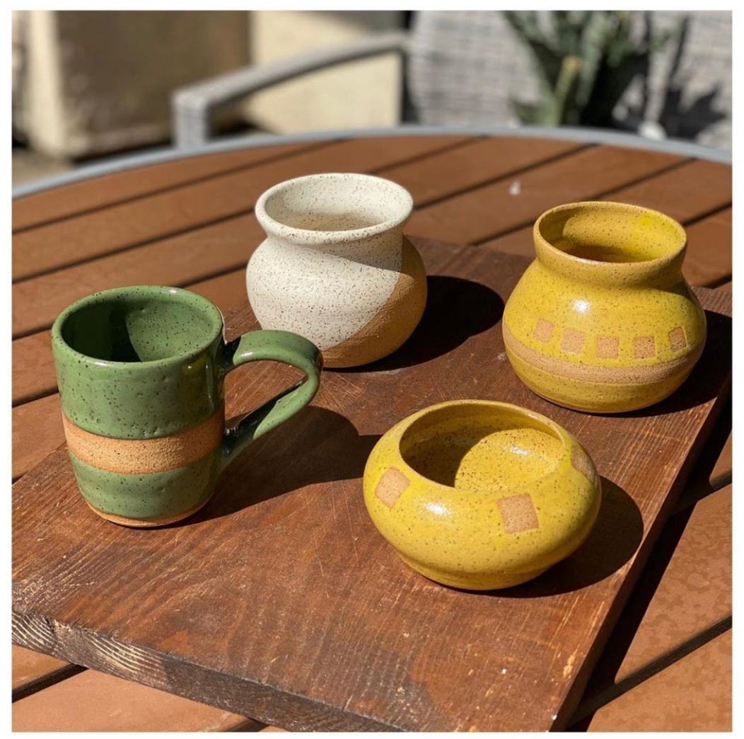 Set of four small items made by Dr. Camacho. Lower left item is a green mug. Lower right item is a small yellow bowl. Upper right item is a small yellow pot. Upper left item is a small cream and light brown pot. The two pots are roughly the same shape.