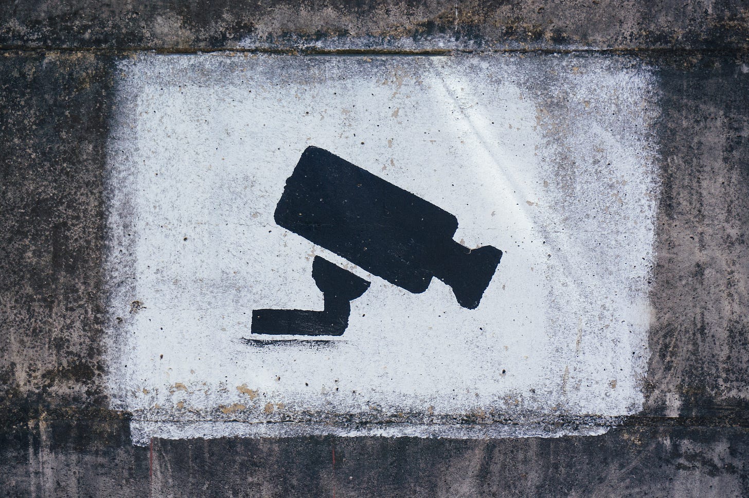 A photo of a graffiti stenciled surveillance camera.