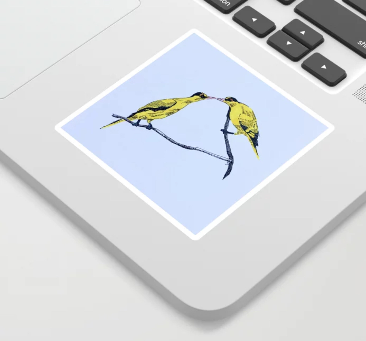 photo of Commitment art as a sticker on a laptop. Two bright yellow black-naked oriole birds perched on a branch, with their beaks touching, like kissing