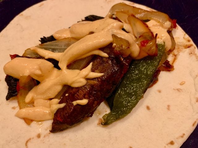 A tortilla with a pile of mushrooms, poblano peppers, and browned onions on top, with a layer of creamy sauce.