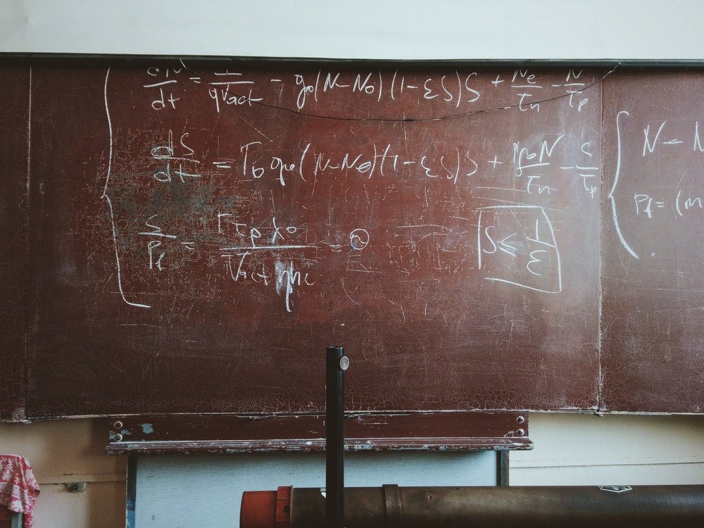 Foto mostra um quadro escolar envelhecido, com fórmulas matemáticas anotadas a giz.