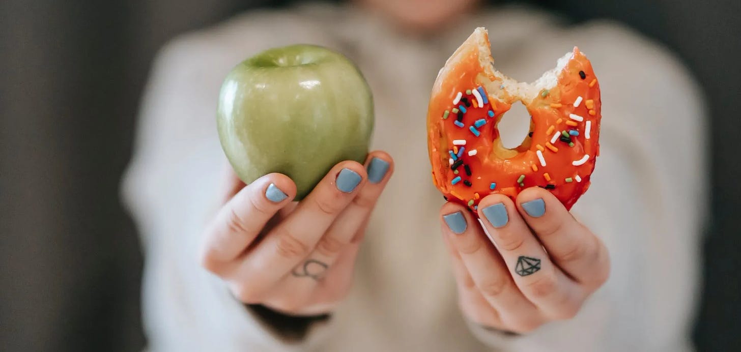 woman showing apple and bitten doughnut
